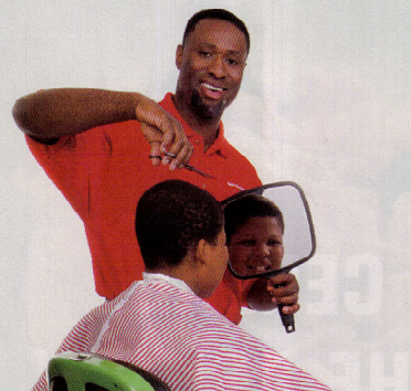 a man in a red shirt is cutting a boy's hair.