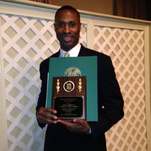 a man in a suit and tie holding an award.